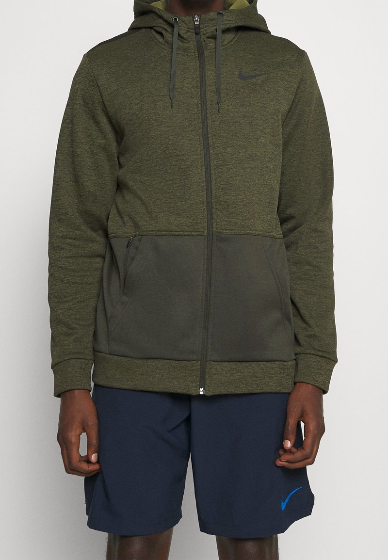 Hoodie zippé vert olive avec un panneau inférieur vert foncé contrastant, poches avant et capuche avec cordon de serrage ; logo Nike sur la poitrine.