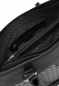 Borsa a mano in pelle nera con tasca anteriore decorata, zip superiore aperta e scomparto interno con zip visibile.