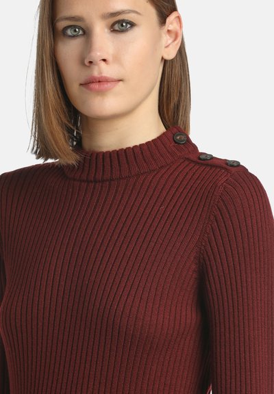 Pull en rib rouge bourgogne à col montant avec quatre boutons noirs décoratifs à l'épaule, présentant un design ajusté et un tissu texturé.