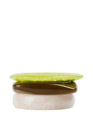 Tres piedras lisas, planas y redondeadas apiladas, con la superior verde, la del medio marrón y la inferior beige pálido, sobre un fondo blanco.