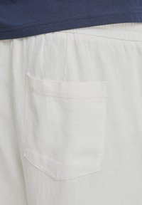 Hvide hørshorts med en struktureret finish, der har en enkelt påsyet lomme bagpå samt elastik i taljen.