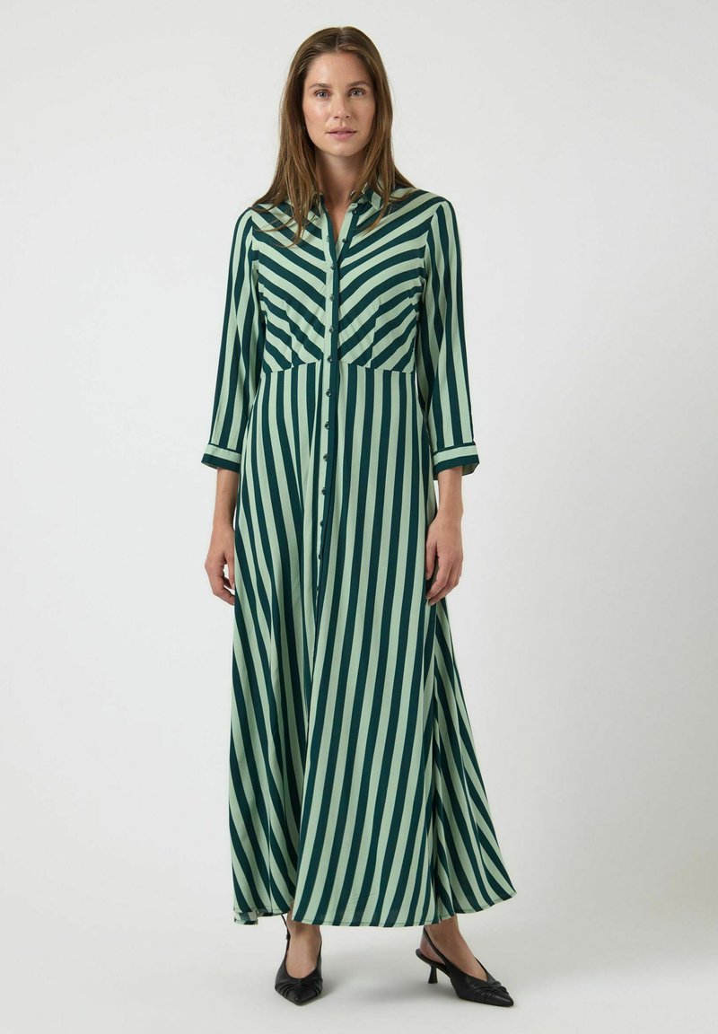 Dlouhé šaty se zeleno-krémovými pruhy z hladké látky, s zapínáním na knoflíky vpředu, límečkem a tříčtvrtečními rukávy.