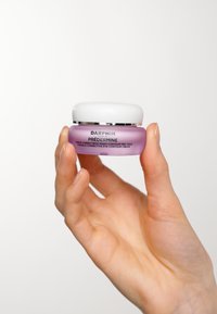 Crema contorno occhi Darphin Prédermine in un barattolo di vetro viola con un coperchio bianco, con accenti argentati e testo stampato sul lato.