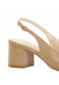 Beige slingback schoen met een blokhak. Gladoppervlak, ronde neus en een gouden gespsaccent op de band voor een veilige sluiting.