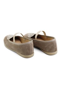 Zapatos de ante beige tipo slip-on con un acento texturizado en beige, suela plana y tiras elásticas en el talón. Acabado suave con forma redondeada.