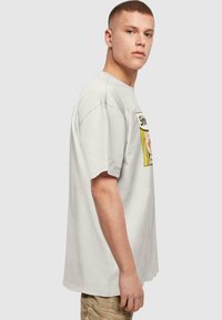 Camiseta de algodón en gris claro, con mangas cortas y un estampado gráfico rectangular en colores vibrantes en la parte delantera.