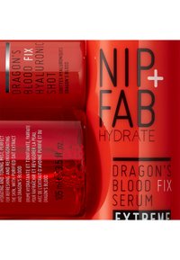 Bottiglie di plastica rossa con marchio "NIP+FAB", etichettate "Dragon's Blood Fix" e "Hyaluronic Shot", contenenti un liquido trasparente e dettagli in rilievo.