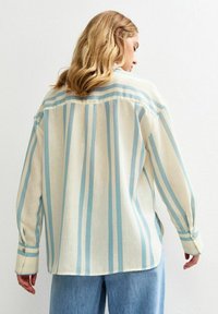 Camicia leggera a strisce in crema e blu chiaro, con una vestibilità morbida, maniche lunghe e polsi standard con bottoni.