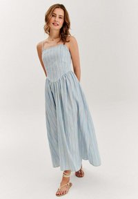 Pasiasta sukienka na lato w jasnoniebieskim kolorze z pastelowymi poziomymi paskami, dopasowana góra i rozkloszowany dół. Posiada cienkie ramiączka.