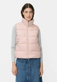 Hellrosa gepolsterte Weste mit hohem Kragen und Reißverschluss, die seitliche Taschen und eine glatte Textur aufweist, getragen über einem grauen Langarmoberteil.