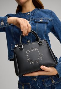 Sort håndtaske lavet af glat læder, med et cirkulært design og sølvnitter. Tasken har to korte håndtag og lynlås lukning.