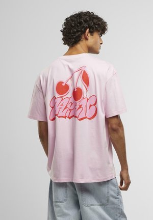 T-shirt en coton rose avec un grand graphisme de cerise rouge et un texte de style graffiti au dos. Manches courtes et coupe décontractée.