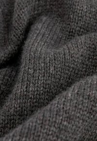 Tissu tricoté texturé de couleur gris foncé présentant un motif côtelé avec des fils visibles, évoquant chaleur et douceur.