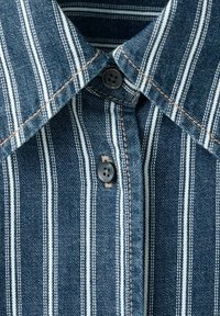 Blauer und weißer, vertikal gestreifter Jeanshemdkragen mit zwei schwarzen Knöpfen und sichtbarer brauner Naht.