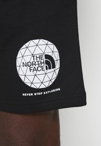 Černé bavlněné tričko s geometrickým bílým logem a textem "The North Face" s nápisem "NEVER STOP EXPLORING" pod ním.