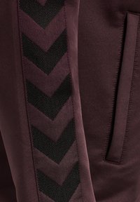 Joggers burdeos con un patrón en chevron negro texturizado a lo largo del costado, con un acabado suave y detalles de bolsillo oculto.