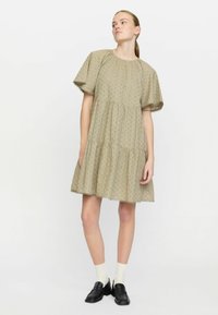 Lys beige, broderet bomulds kjole med korte puff-ærmer, lagdelt design, scallop-kant og subtile blomster mønstre.