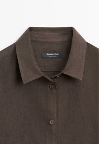 Donkerbruine overhemdkraag met twee zichtbare knopen en een Massimo Dutti merklabel binnenin de nek.
