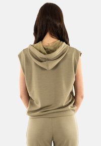 Sudadera sin mangas de color verde oliva con una textura suave, que cuenta con una capucha en capas, un corte relajado y costuras visibles en la parte posterior.