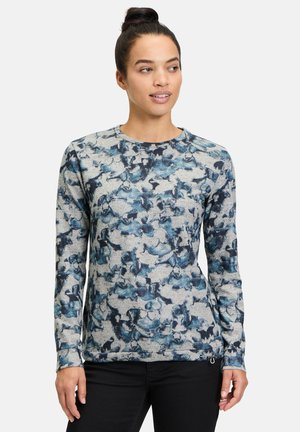 Long-sleeve top in textured gray fabric with blue abstract pattern, featuring a round neckline and fitted style. Black pants visible.