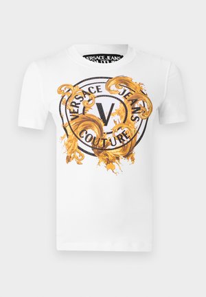 Valge lühikeste varrukatega t-särk, millel on ees must ringikujuline "Versace Jeans Couture" logo ning kaunid kuldsed barokkstiilis keerutised.