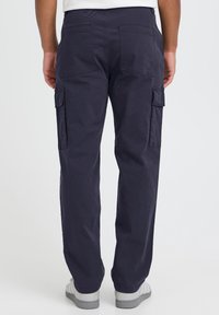 Tovorne hlače v temno mornarsko modri barvi, iz bombaža. Imajo stranske žepke in zadnje žepke z obliži. Sproščen kroj s pravimi hlačnicami.