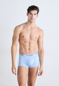 Herren Unterhosen in Hellblau aus glattem Stoff mit einem elastischen Bund, der das schwarze "Calvin Klein" Logo trägt.