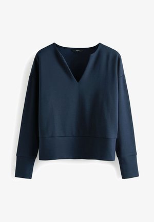 Top de manga larga azul marino con cuello en V, hecho de una tela suave. Presenta un diseño corto y puños anchos.
