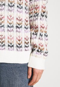 Strickpullover mit mehrfarbigem Zickzackmuster in Pink-, Weiß- und Schwarztönen. Gerippte Bündchen und Saum. Grobe Textur, taillierte Ärmel.