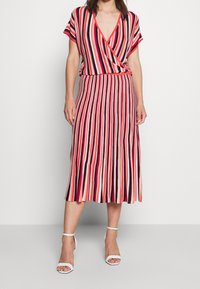 Abito a righe con maniche corte, scollatura a V e gonna svasata in rosso, nero e panna. Presenta una vita cinte e una texture liscia.