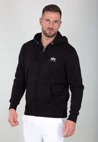 Felpa con zip nera realizzata in tessuto morbido, con logo sul petto, cappuccio regolabile con coulisse e tasche a marsupio.