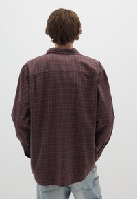 Camicia a maniche lunghe in flanella bordeaux con motivo a griglia bianca, caratterizzata da una vestibilità comoda e colletto, vista dal retro.
