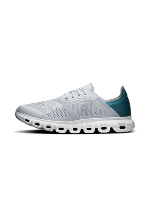 Chaussure de sport gris clair avec talon bleu, fermeture à lacets, dessus en mesh respirant et semelle blanche segmentée pour l'amorti.