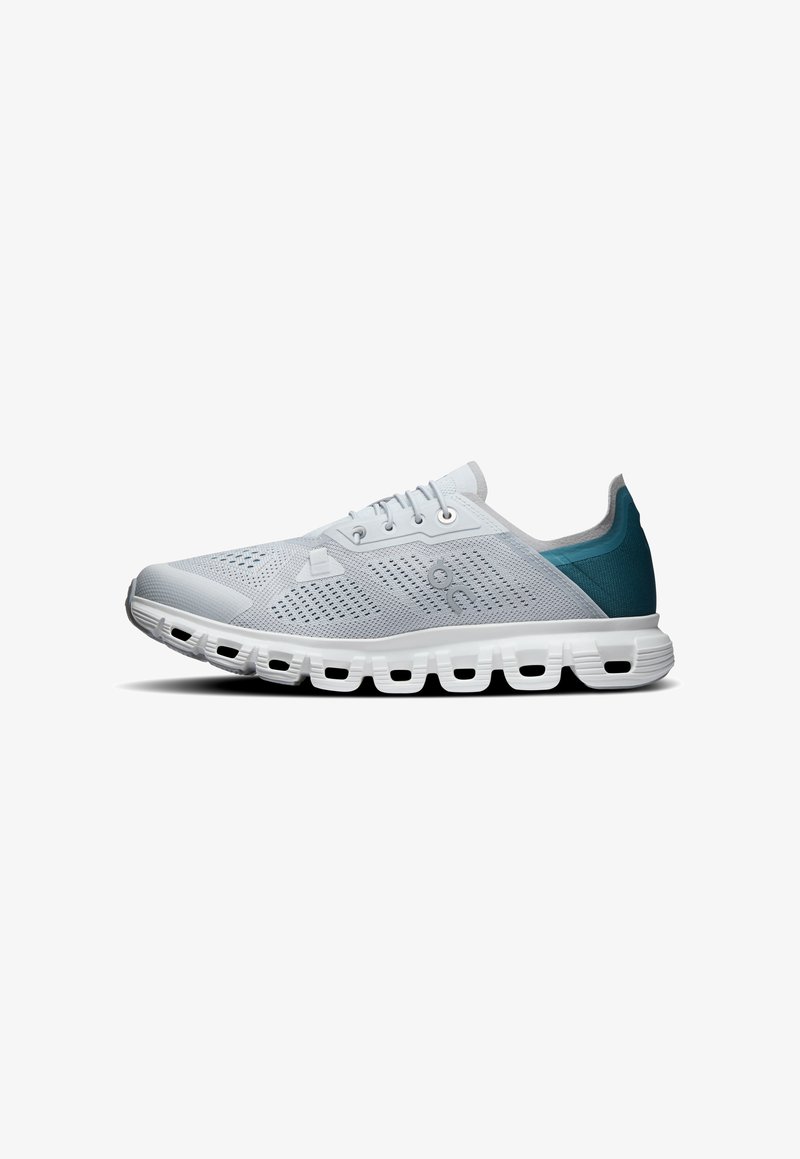 Chaussure de sport gris clair avec talon bleu, fermeture à lacets, dessus en mesh respirant et semelle blanche segmentée pour l'amorti.