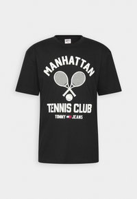 Juoda medvilninė marškinėliai su baltu tekstu "MANHATTAN TENNIS CLUB," perbrauktais teniso raketėmis ir Tommy Jeans logotipu. Trumpomis rankovėmis, apvalia iškirpte.