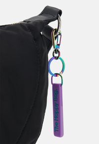 Sac noir avec un fermoir métallique multicolore et un anneau attachés à une étiquette de porte-clés violette portant l'inscription « The Happy Bag ».