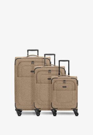Three tan fabric suitcases in varying sizes with black wheels and handles. Each has a smooth surface with a subtle texture and stitching detail.