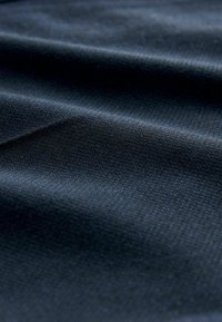 Donkerblauwe stof met een getextureerd weefsel, met subtiele kleurvariaties en onregelmatigheden. Het oppervlak lijkt glad met lichte kreukjes.