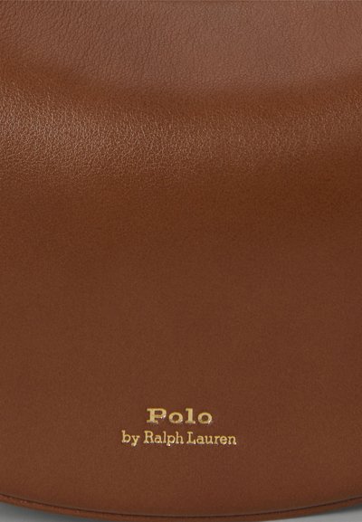 Brūns ādas soma ar gludu tekstūru un noapaļotu formu. Zelta "Polo by Ralph Lauren" logo izcelts.