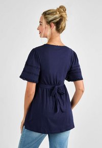 Tengerészkék tunika rövid puffujjakkal, csipke részletekkel és megkötős derékkal. Puha anyag és laza fazon a kényelem érdekében.