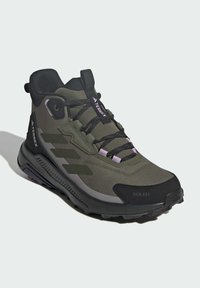 Green and black athletic shoe with a textured upper, lace-up design, and a chunky sole. Features include a cushioned collar and logo accents.
