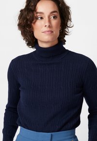 Pull en col roulé bleu marine à côtes avec motif texturé, fabriqué en maille douce, doté de manches longues ajustées et d'un col haut.