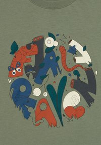 Grön tygtröja med ett cirkulärt tryck som har multikolorade bokstäver och lekfulla illustrationer av växter, insekter och en snigel.