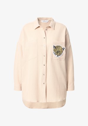Lichtbeige button-up shirt van gestructureerde stof. Voorzien van twee voorzakken en een luipaardprint patch op de linkerzak.