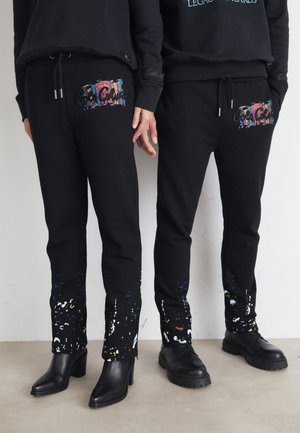 Black sweatpants with colorful splatter patterns, featuring front pockets, an adjustable drawstring waistband, and a tapered leg design.