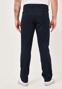 Marineblaue Baumwollhose mit geradem Schnitt, ausgestattet mit Gesäßtaschen, dezentem Nähen und kombiniert mit weißen Sneakers.