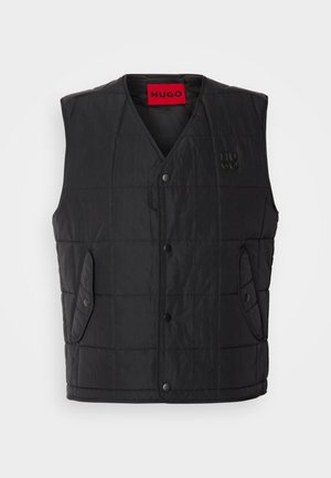 Black padded vest with a V-neck design, featuring snap buttons, two side pockets, and a contrasting red label inside. Textured fabric.