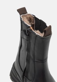 Black leather ankle boot with side zipper, fabric lining, pull tab, and rubber sole. Features a smooth finish and snug fit.