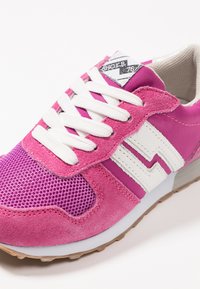 Sneaker sportivo rosa con una combinazione di materiali in mesh e suede, dettagli bianchi, lacci rotondi e una suola in gomma testurizzata.
