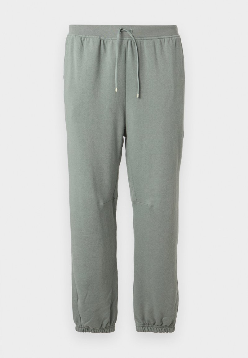 Pantalon de survêtement vert clair avec cordon de serrage, taille et poignets élastiques, présenté sur un fond uni.